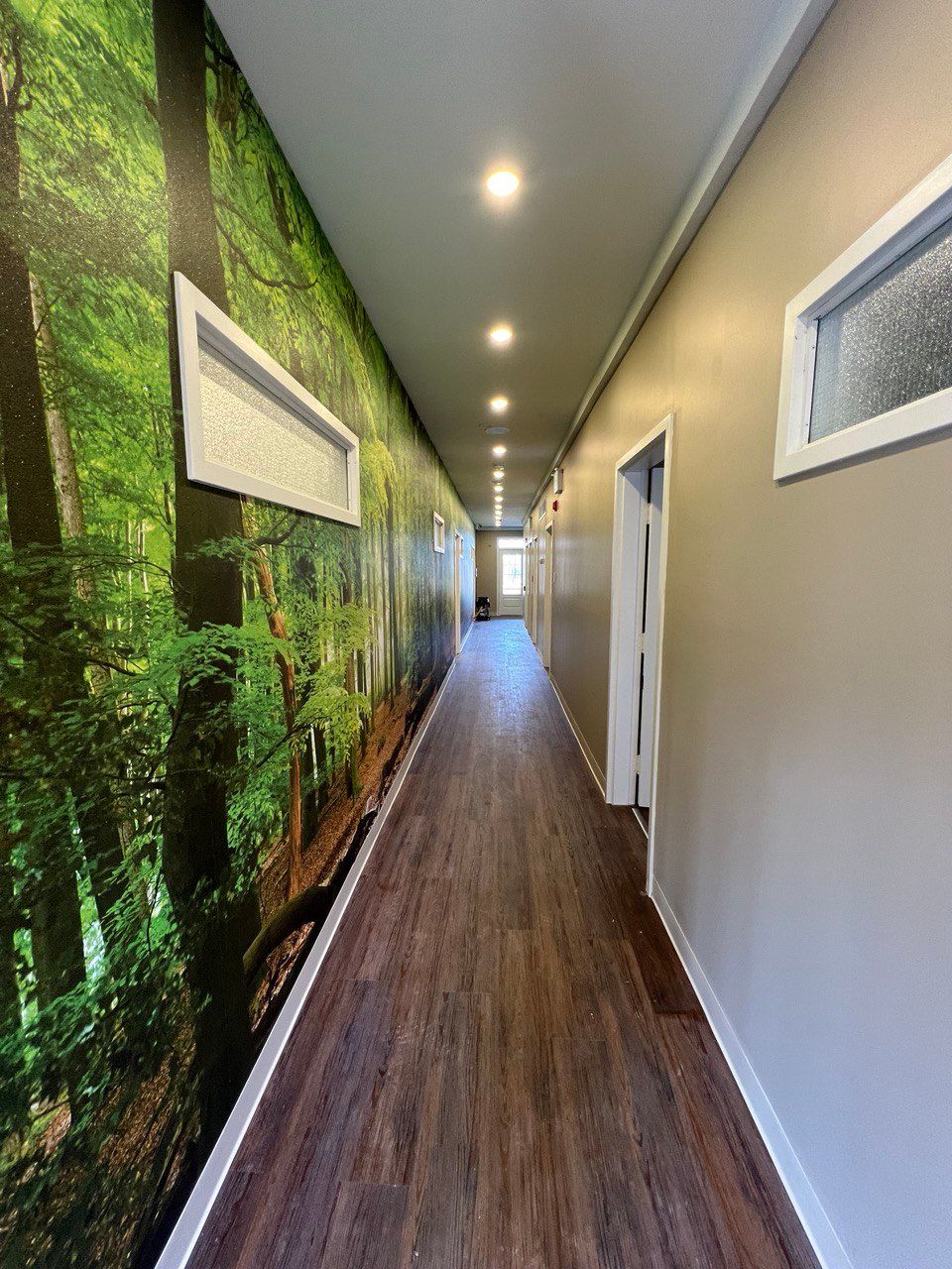 A long hallway with a picture of a forest on the wall.
