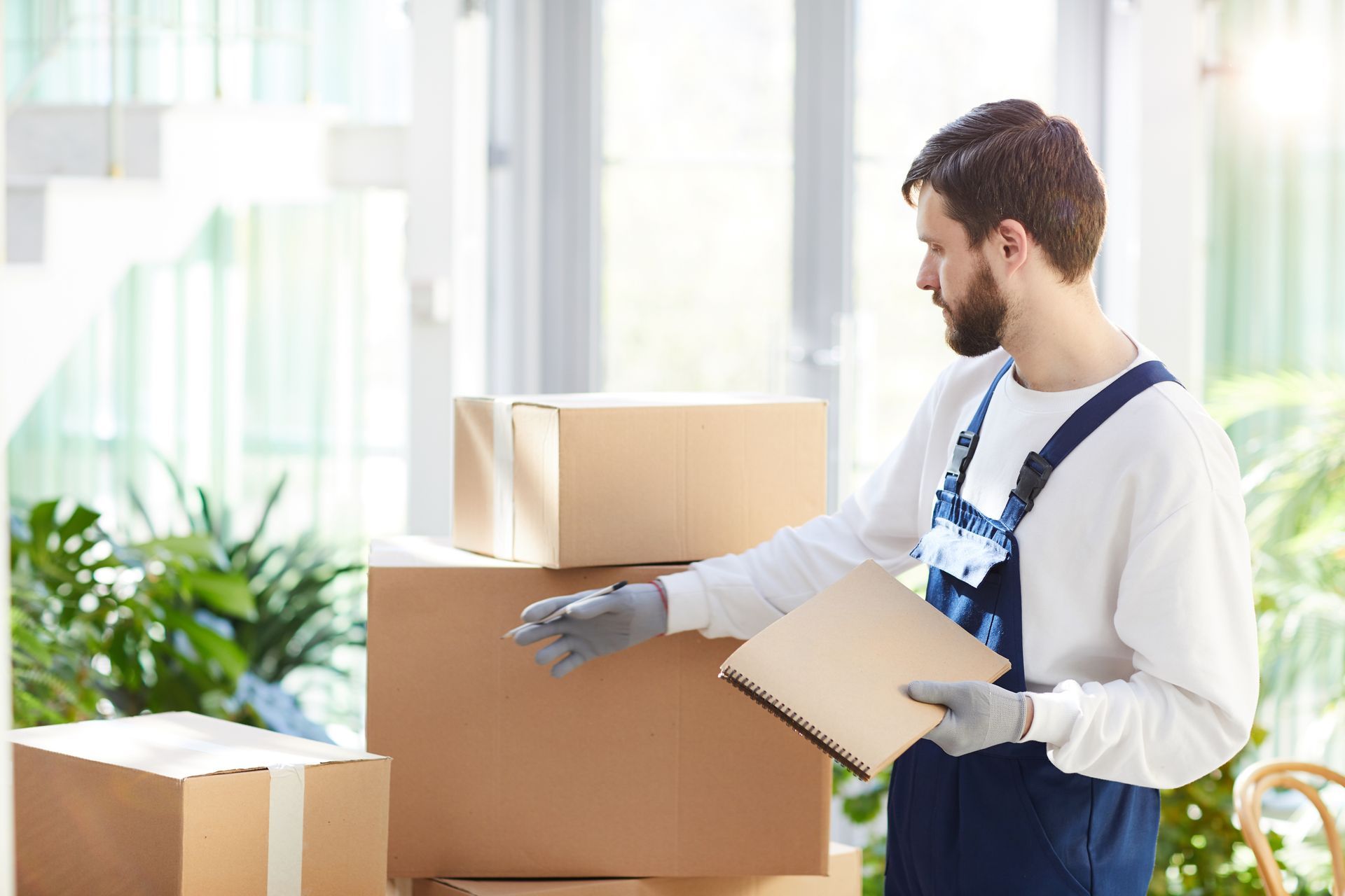 a man is holding a clipboard in front of a pile of cardboard boxes .