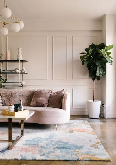 a living room with a couch , coffee table , rug and plant .