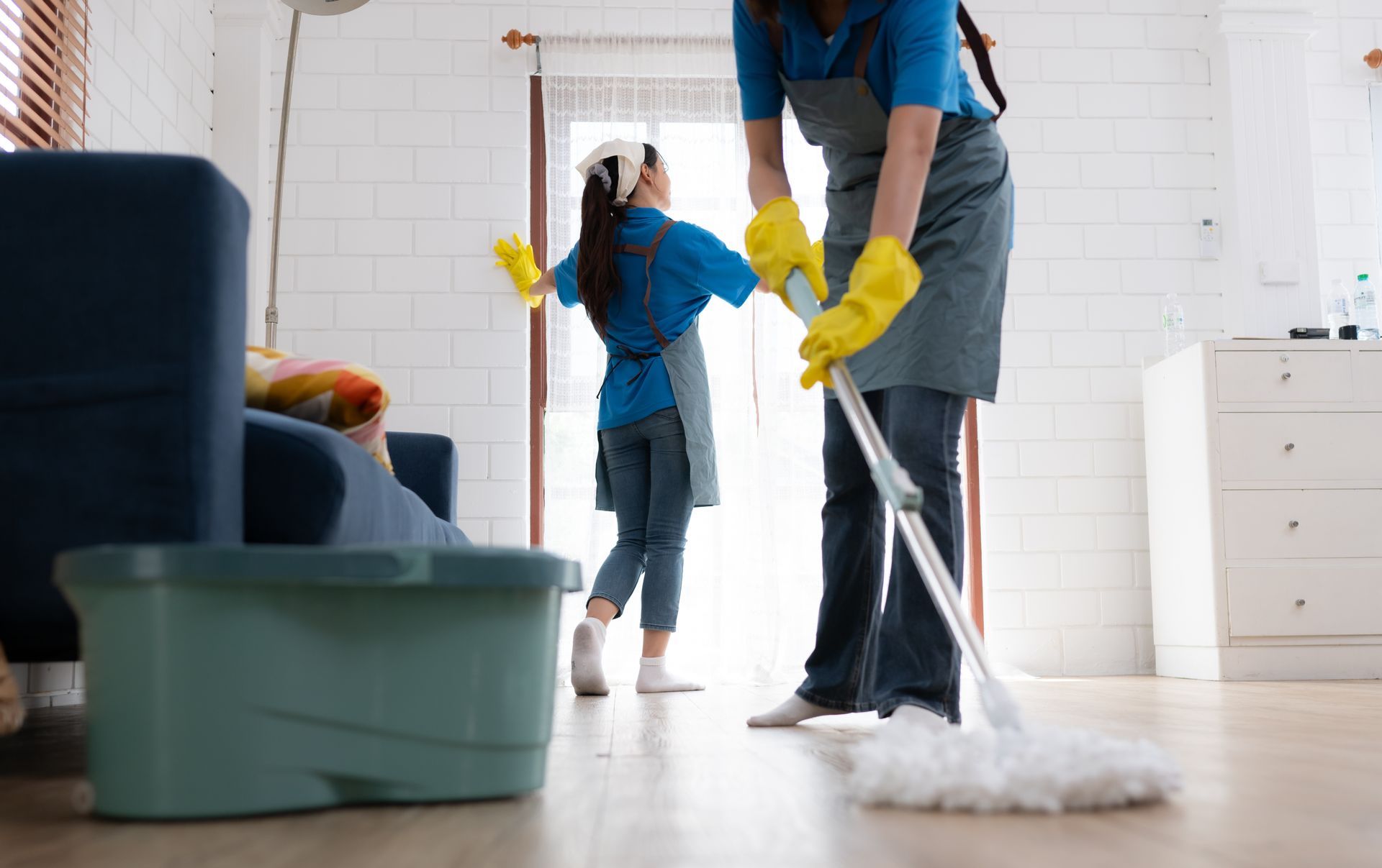 a woman and a little girl are cleaning the floor in a living room .
