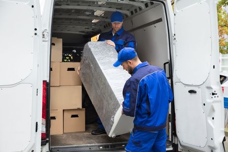 two men are loading a refrigerator into a van .