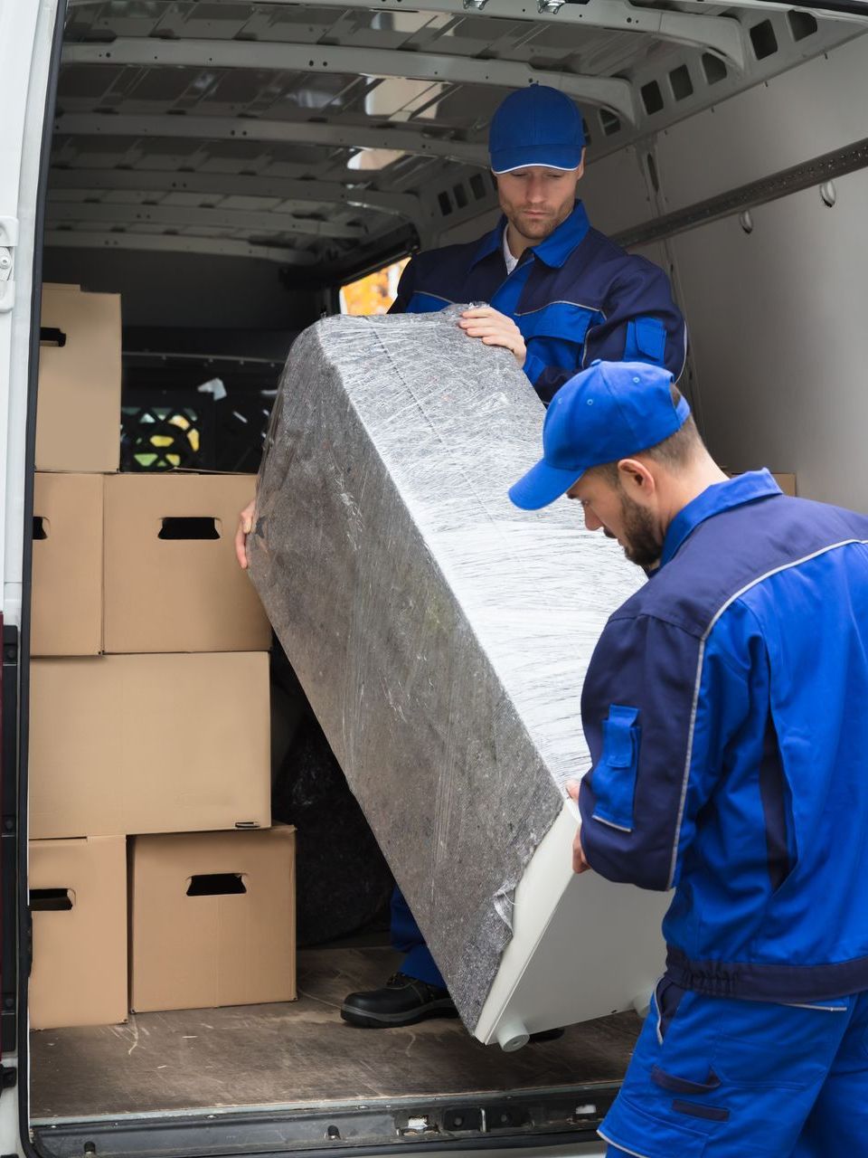 two men are loading a refrigerator into a van .