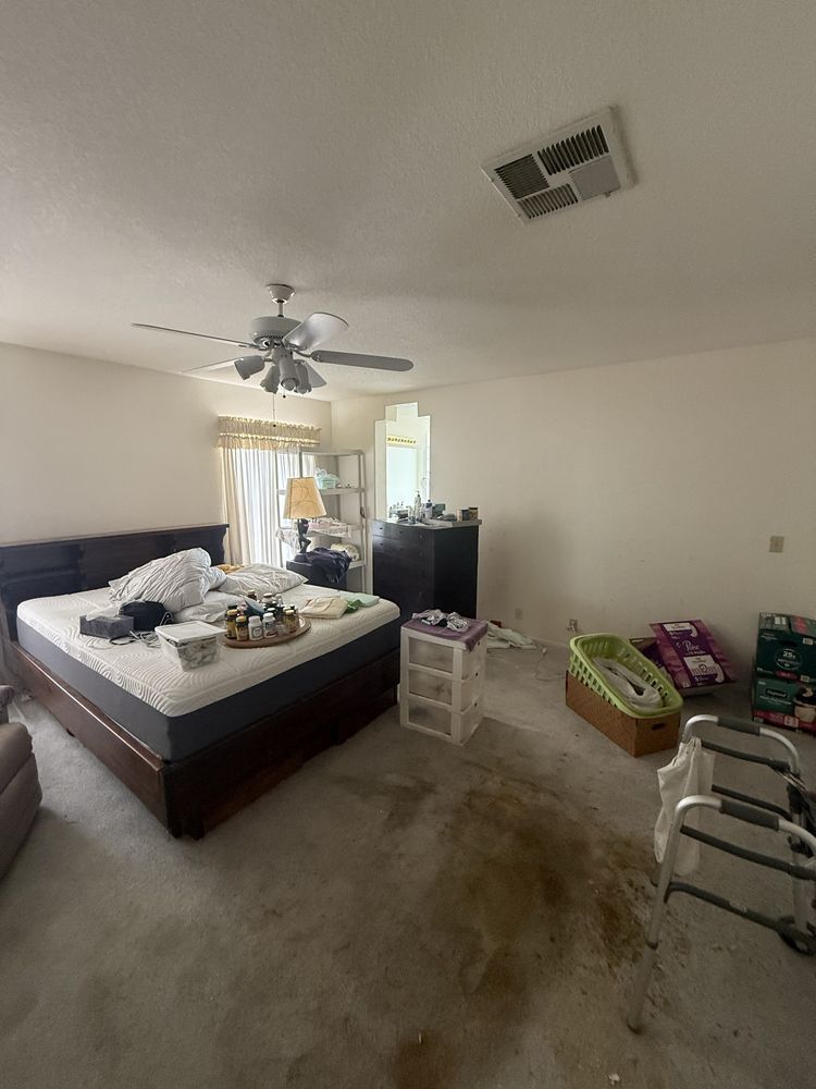 Messy bedroom with unmade bed, ceiling fan, dresser, and clothes scattered on the floor