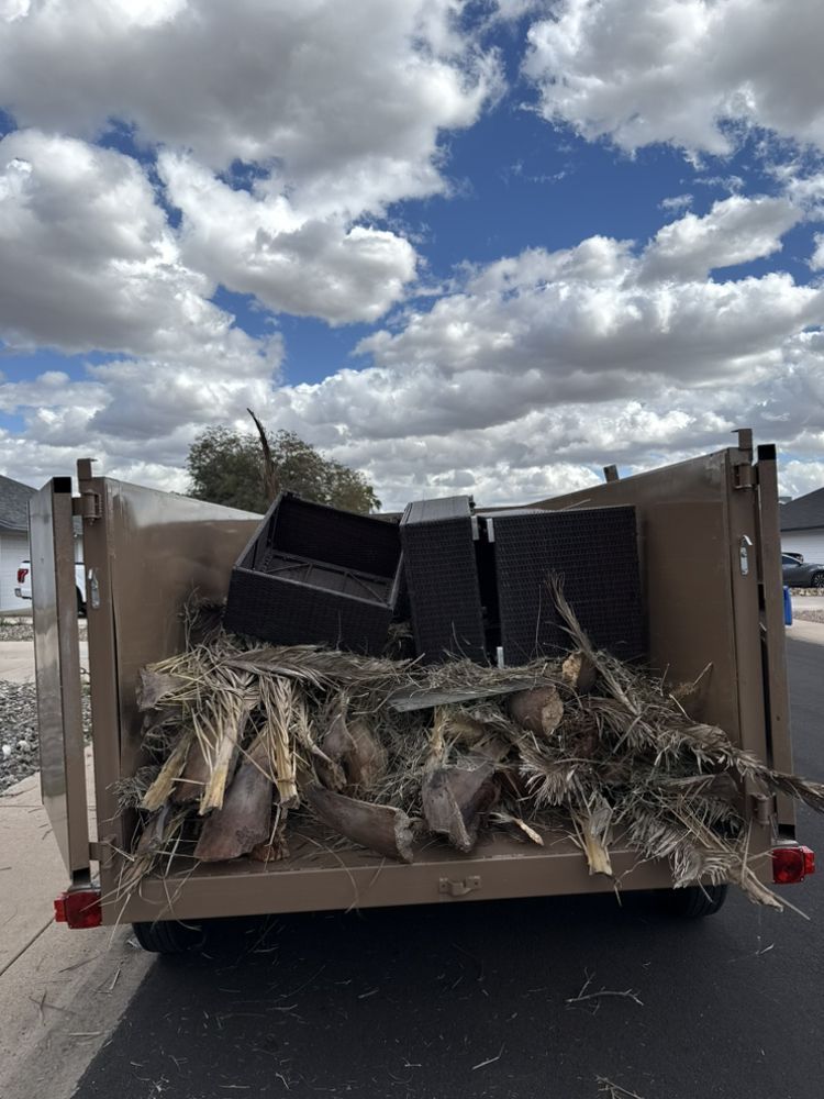 Trailer loaded with palm fronds and black bins under a cloudy sky