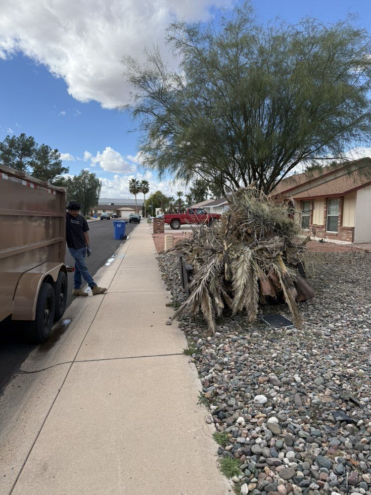 Sidewalk beside moving truck, desert landscaping, and a house under a partly cloudy sky.