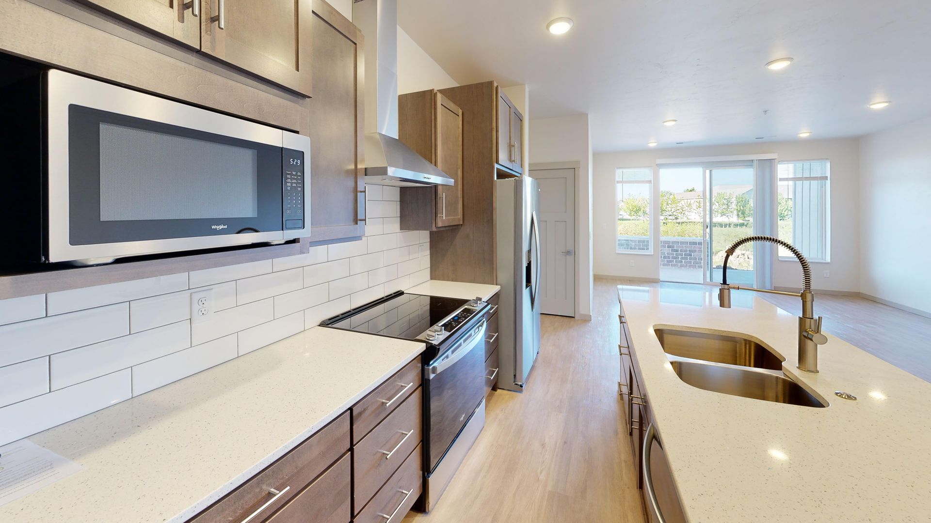 Bright modern kitchen with stainless appliances, white countertops, and an island sink by large windows