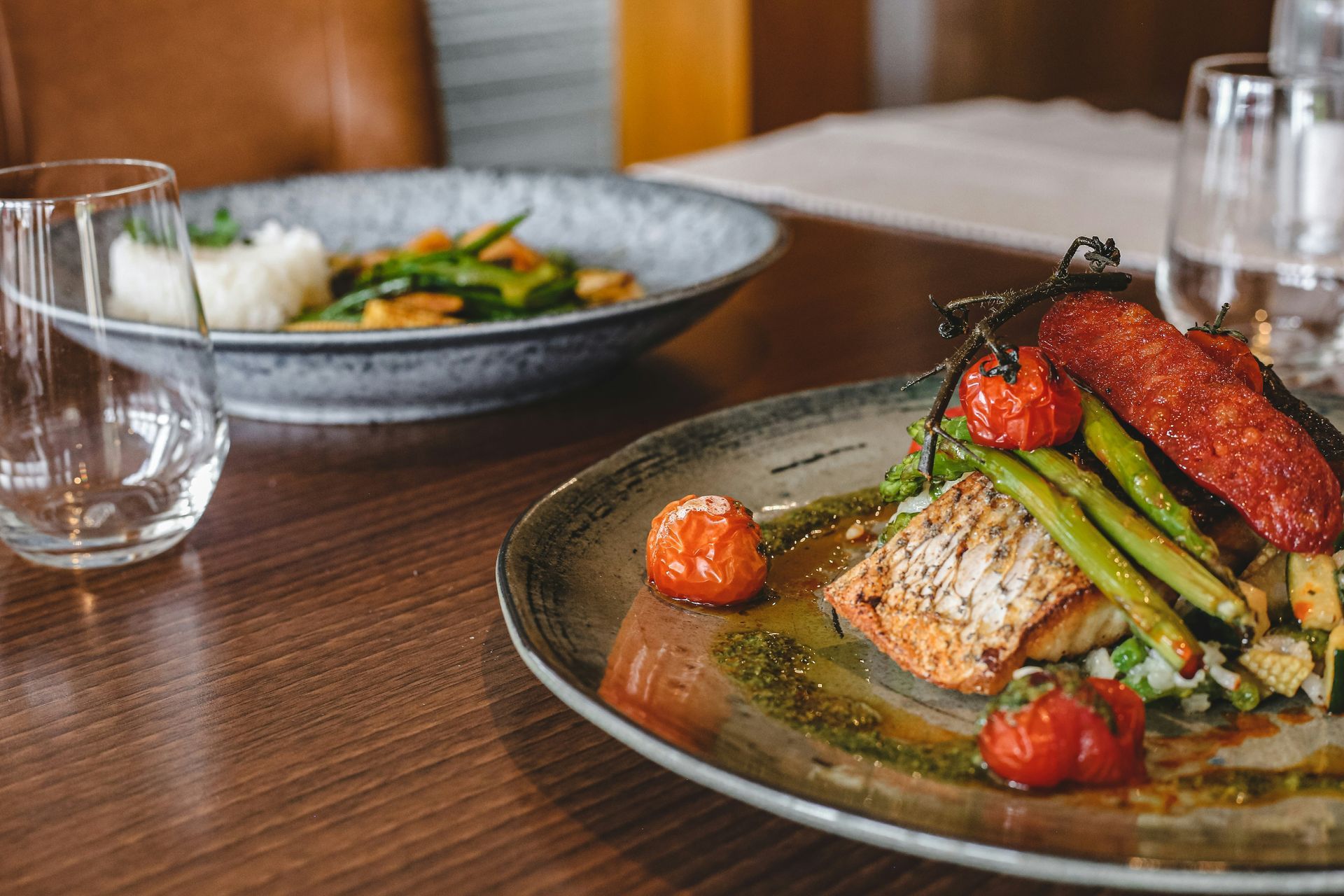 Plated gourmet salmon with asparagus and tomatoes on a wooden dining table