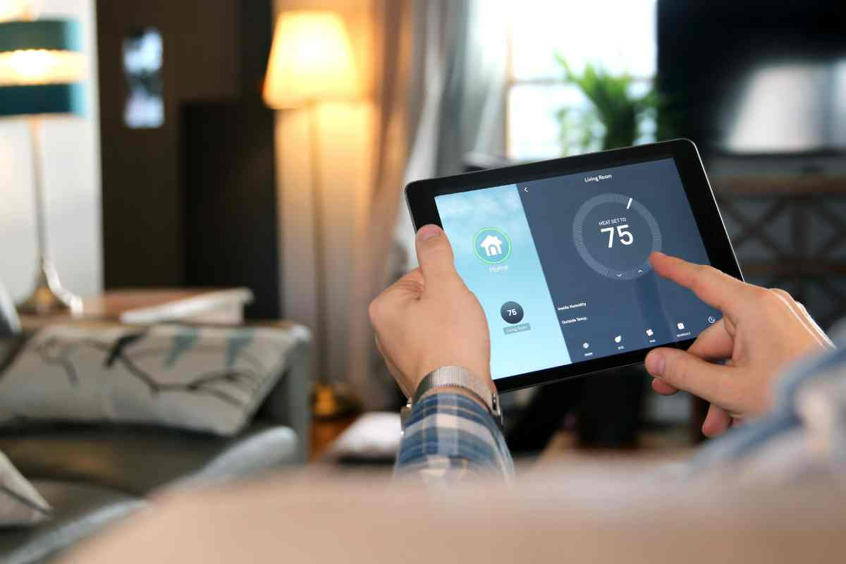 Person using a tablet to control a smart thermostat in a cozy living room