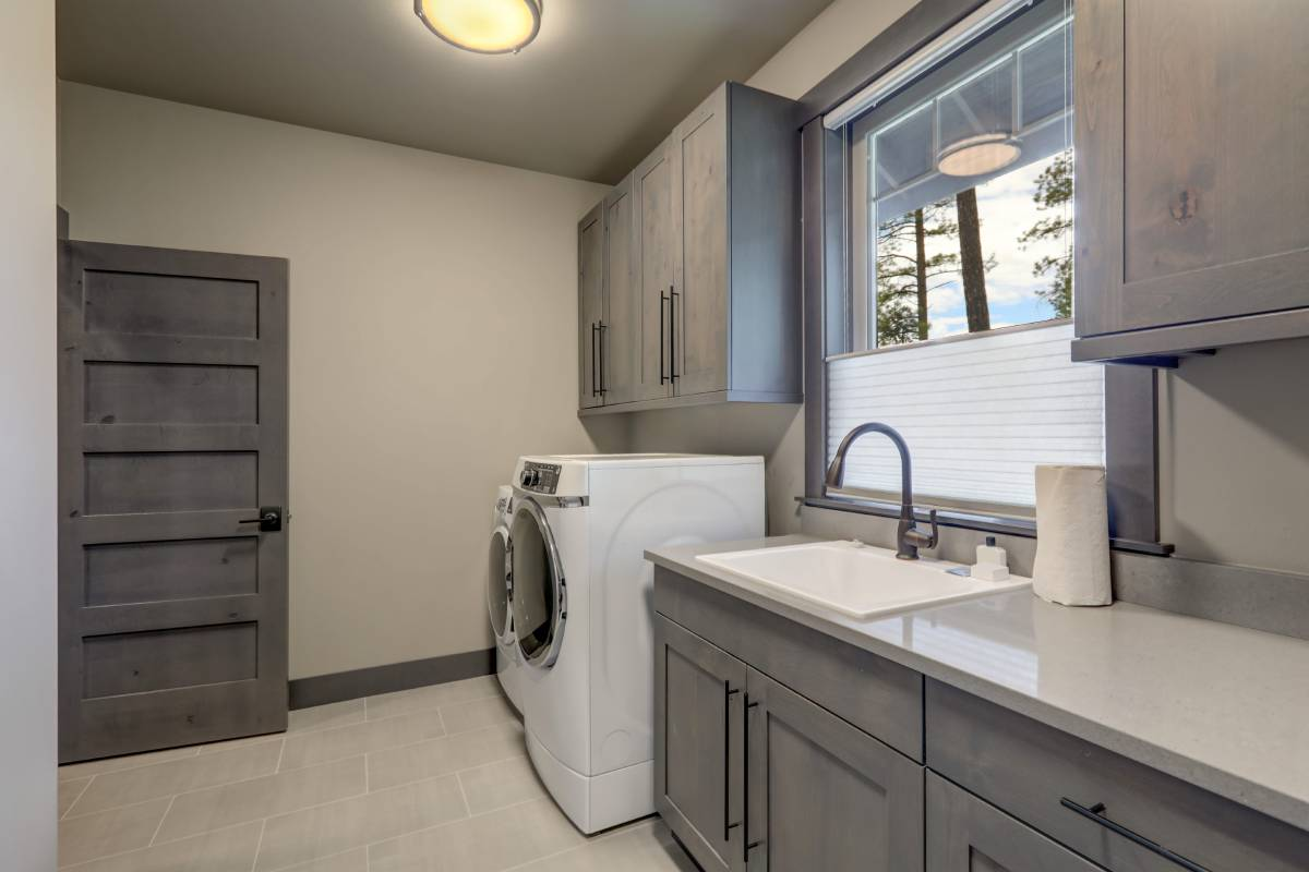 Laundry room with gray cabinets, washer, sink, and window light