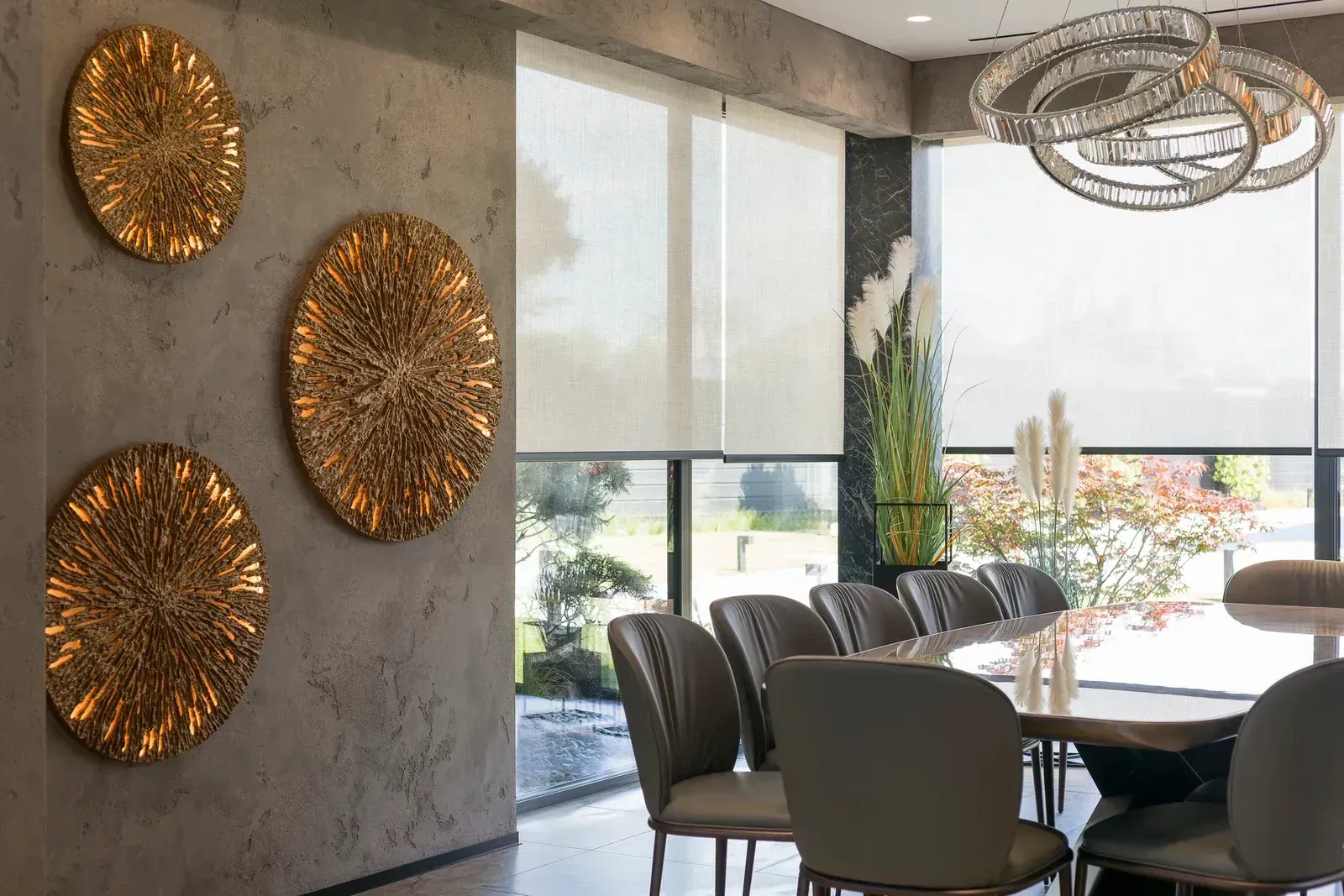 Modern dining room with round table, dark chairs, wall art, and large windows overlooking greenery