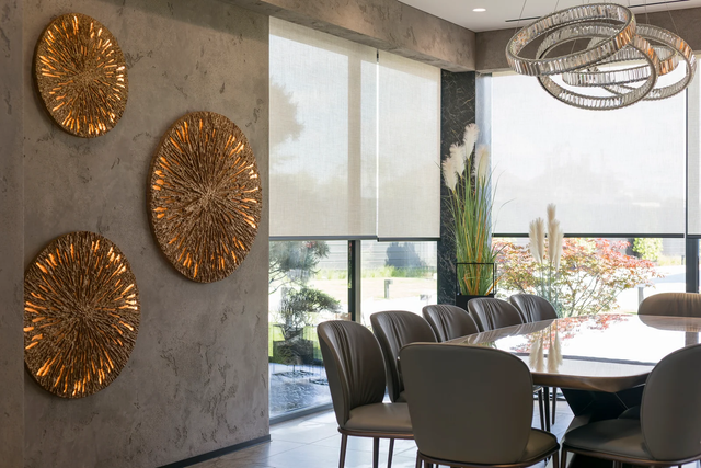 Modern dining room with round table, dark chairs, wall art, and large windows overlooking greenery