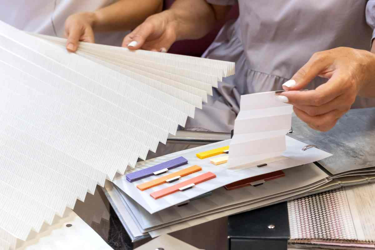 Hands flipping through a binder with color samples and swatches on a table
