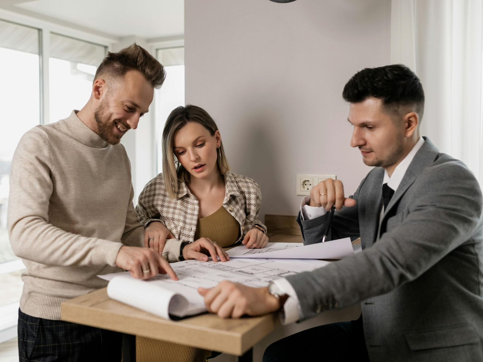 Three people reviewing documents at a table in a bright office