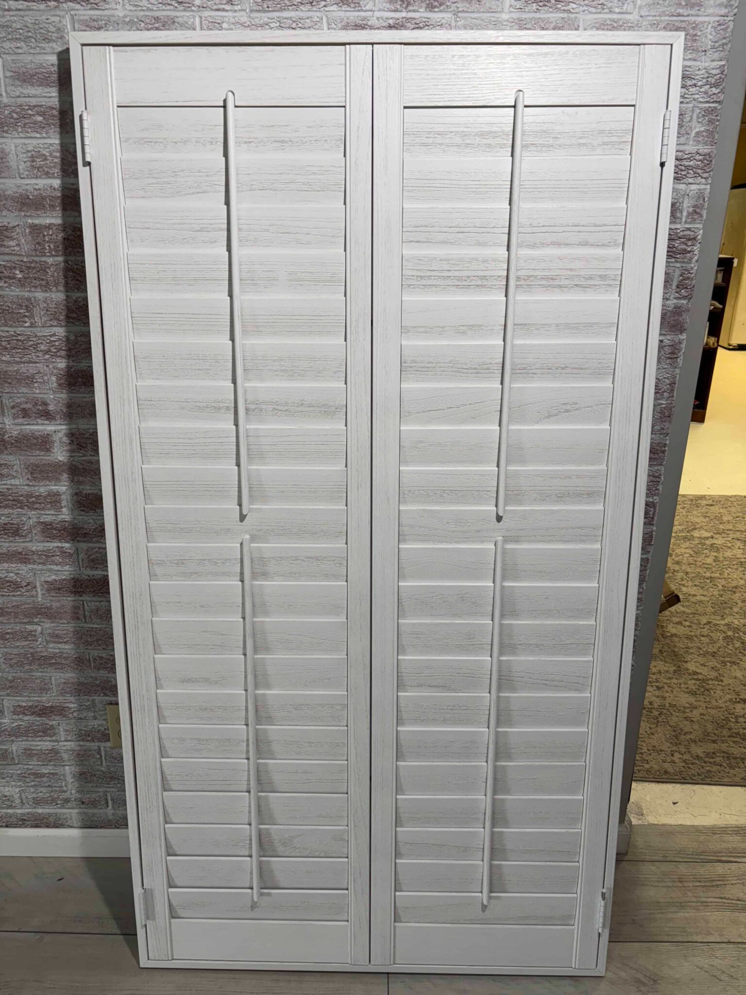 White shutter cabinet doors with slatted panels, leaning outdoors against a wall.