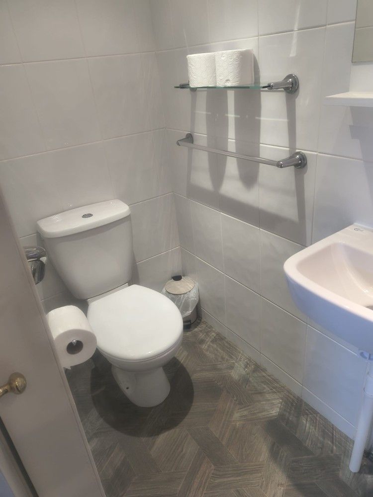 Small bathroom with toilet, towel rack, toilet paper holder, and sink on the right.