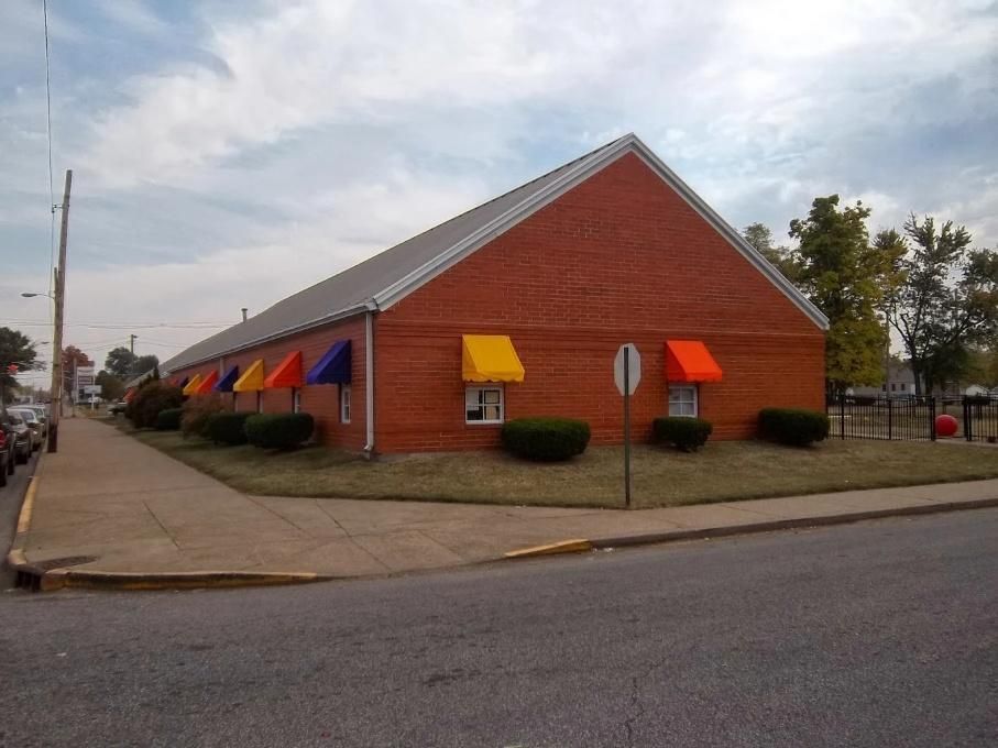 Brick building with colorful awnings on a street corner under a cloudy sky