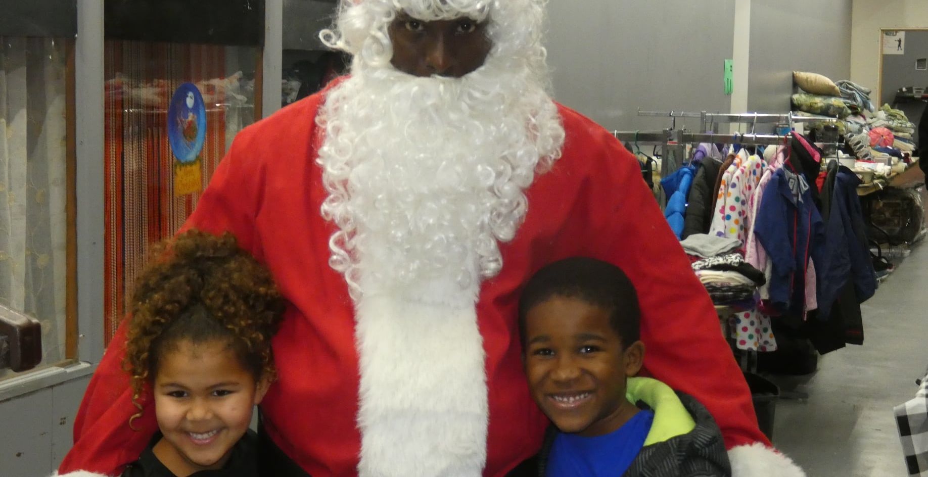 A man dressed as santa claus is posing for a picture with two children.