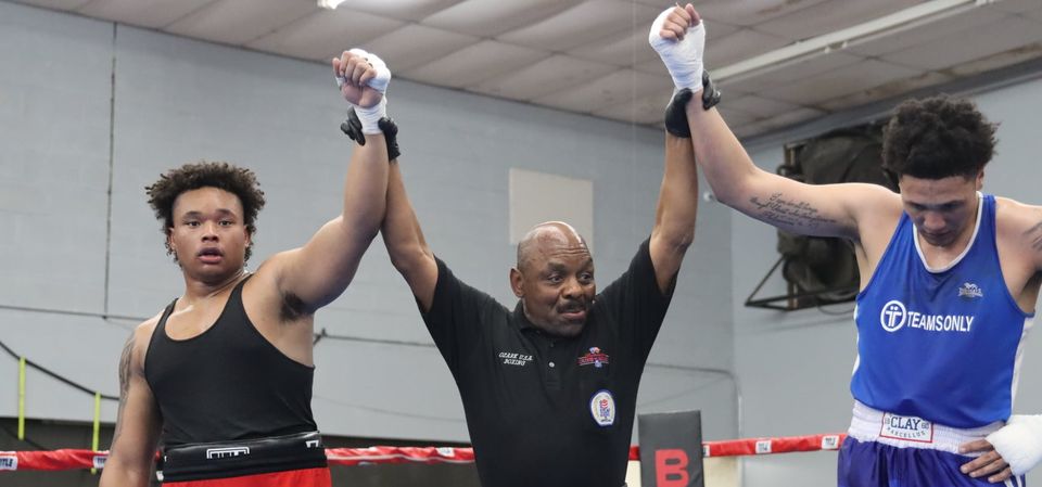 A referee is holding up the hand of a boxer in a boxing ring.