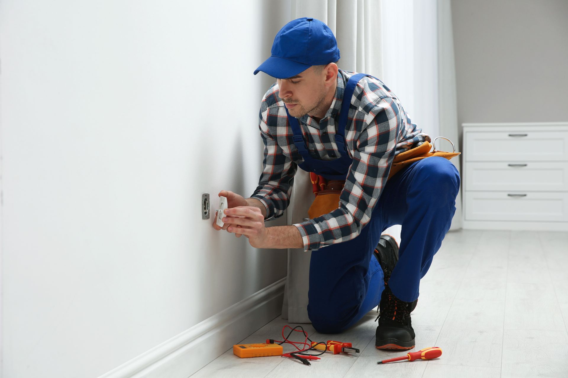 Professional electrician repairing a power socket on a wall inside a room