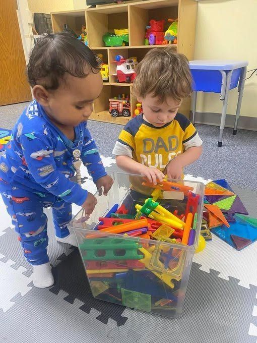 Two children playing with colorful building toys in a classroom.