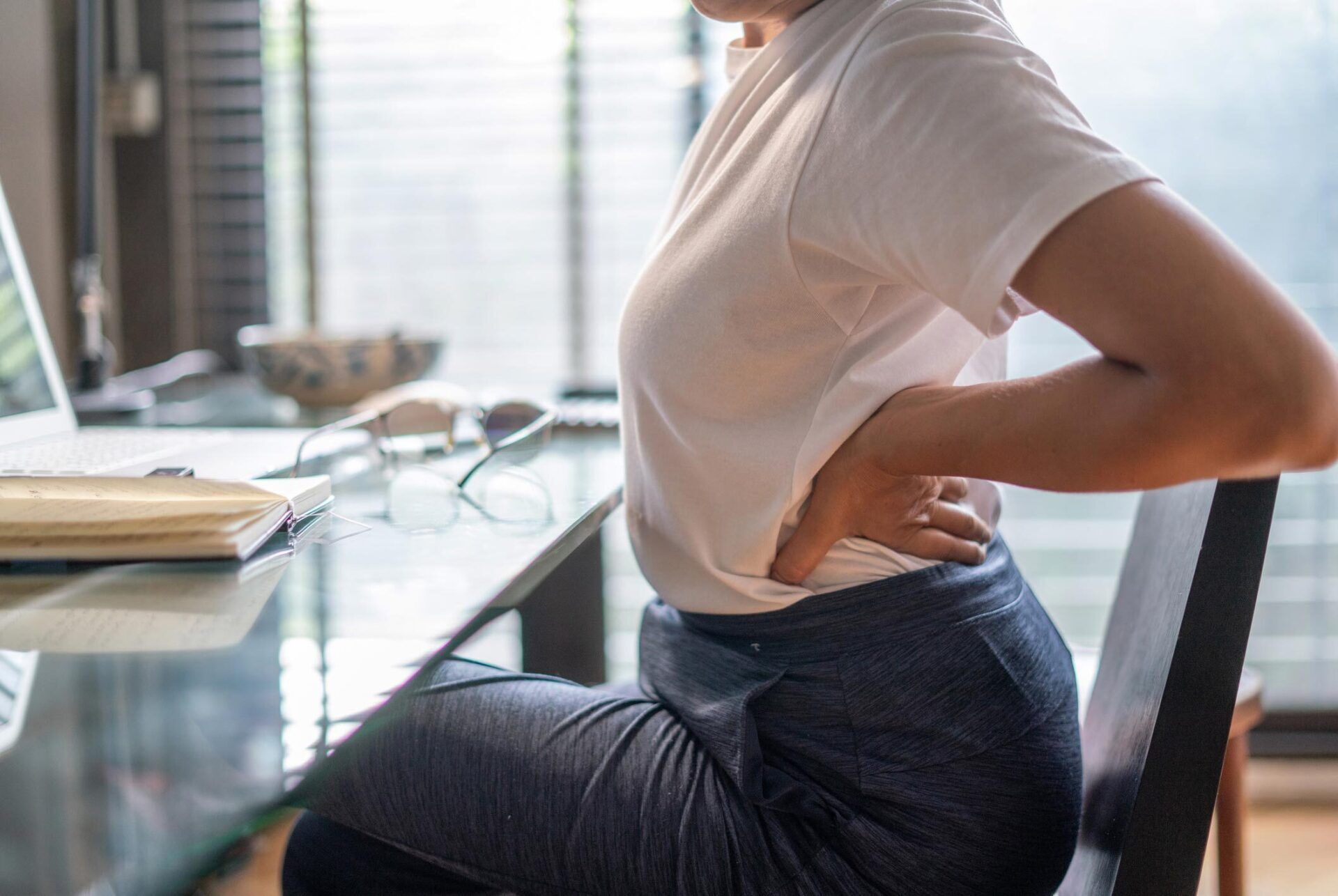 a woman sits at a desk with her hands on her back