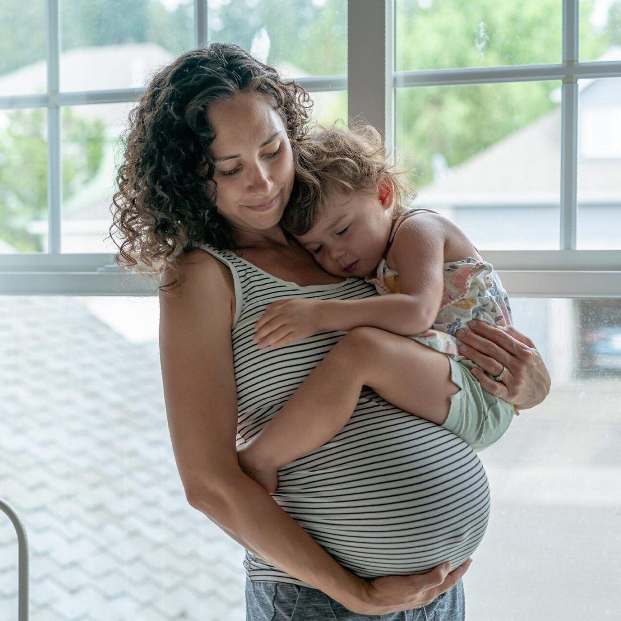 a pregnant woman is holding a little girl in her arms