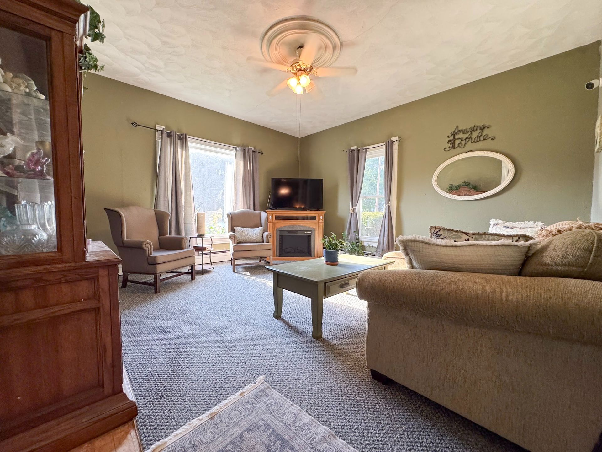 Cozy living room with tan sofa, armchair, TV stand, coffee table, and olive green walls.