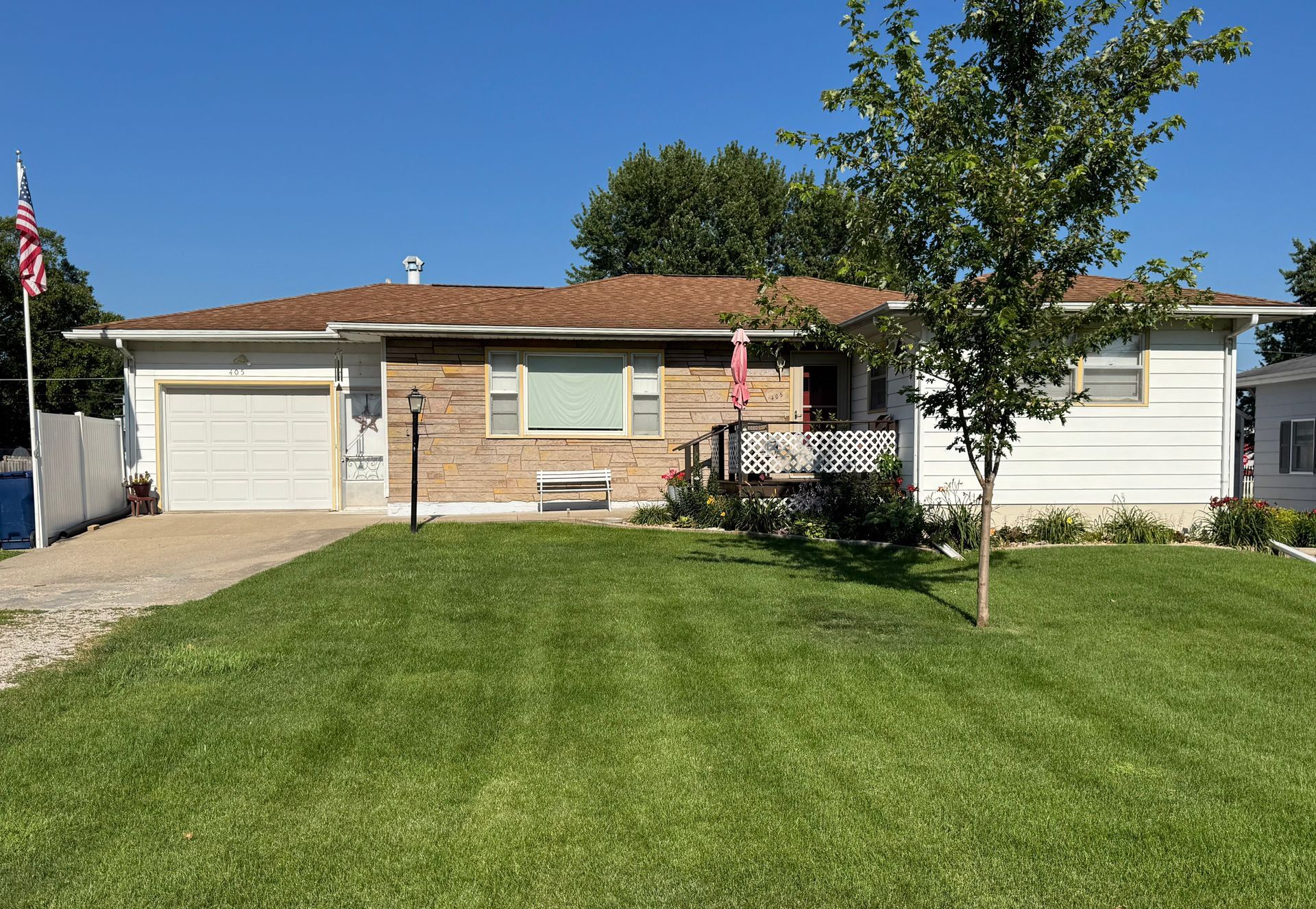 Single-story suburban house with a well-kept lawn, driveway, and small front porch.