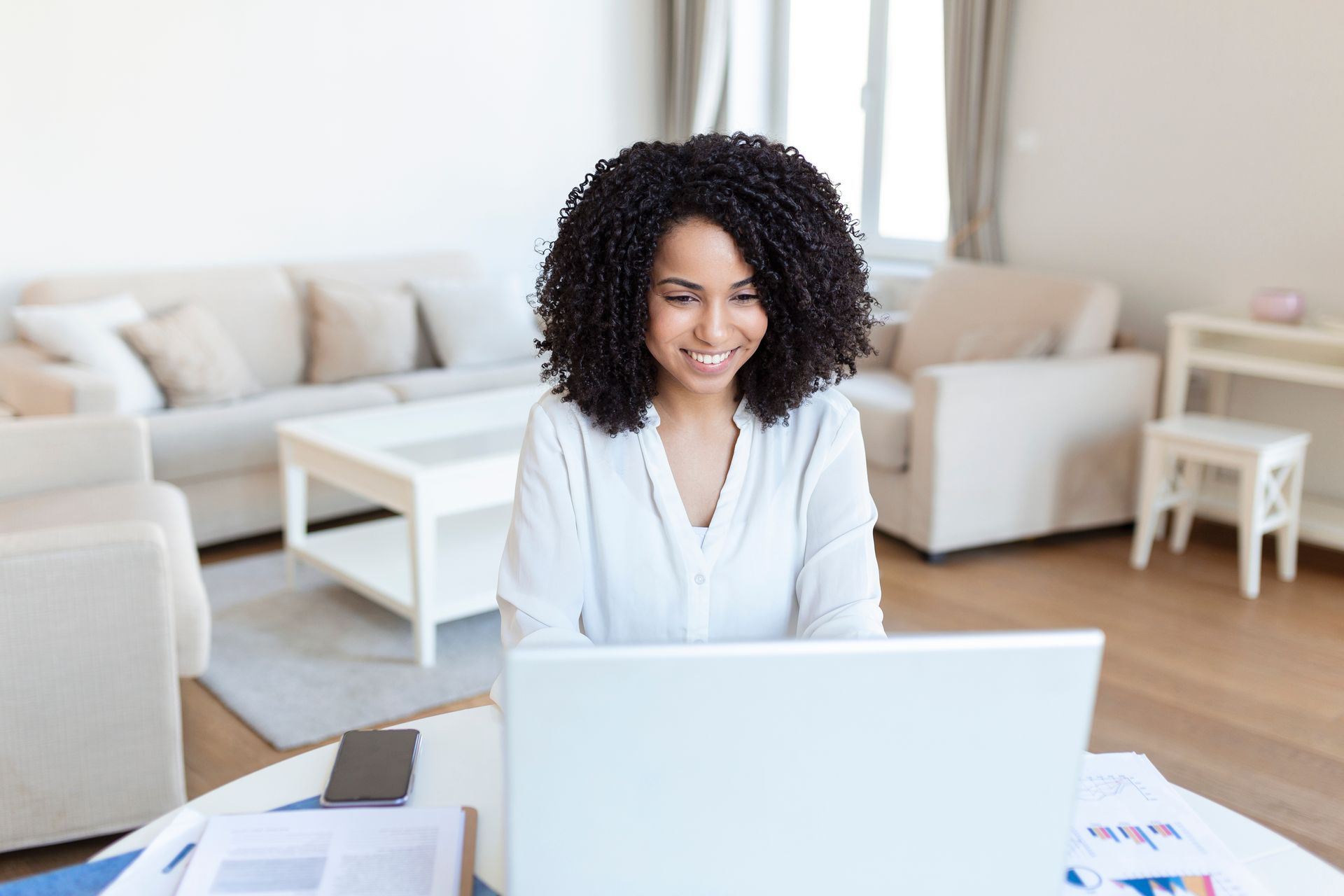 An African American woman sits at a laptop, she has discovered the reasons to hire a life coach
