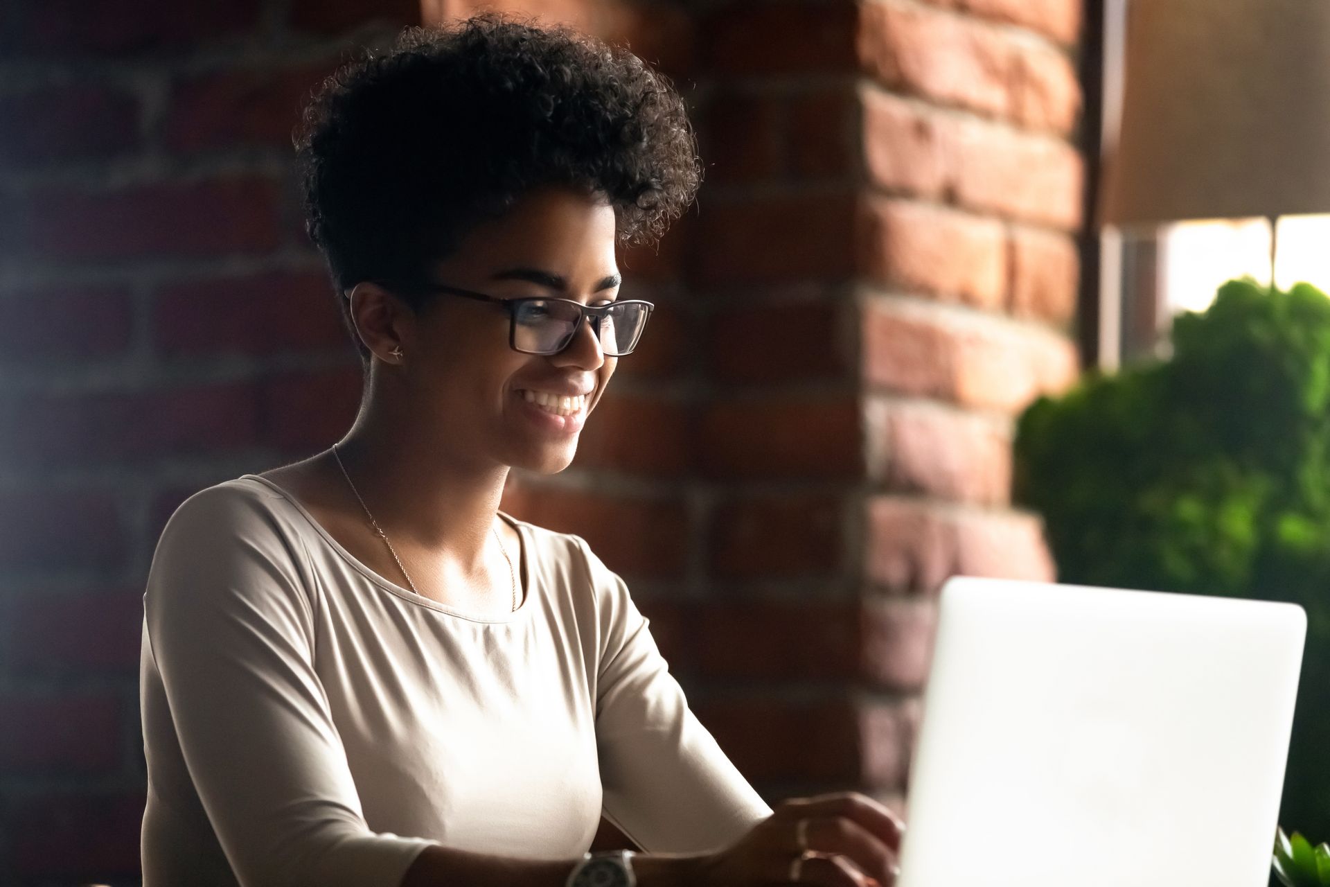 the woman is now smiling, looking at her laptop she is exploring how a mental health coach can help her feel less emotionally overwhelmed