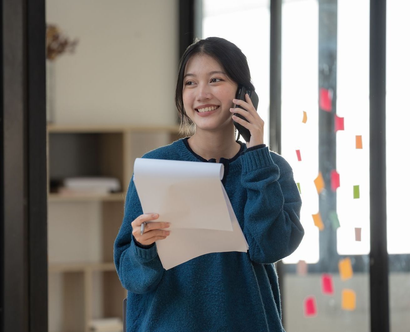 The same yoiung woman smiles while on the phone, she now knows the differences between career coaching vs career counseling