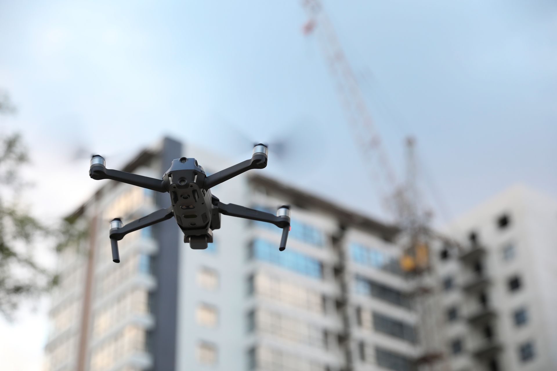 Drone flying in front of a blurred apartment building under a blue sky