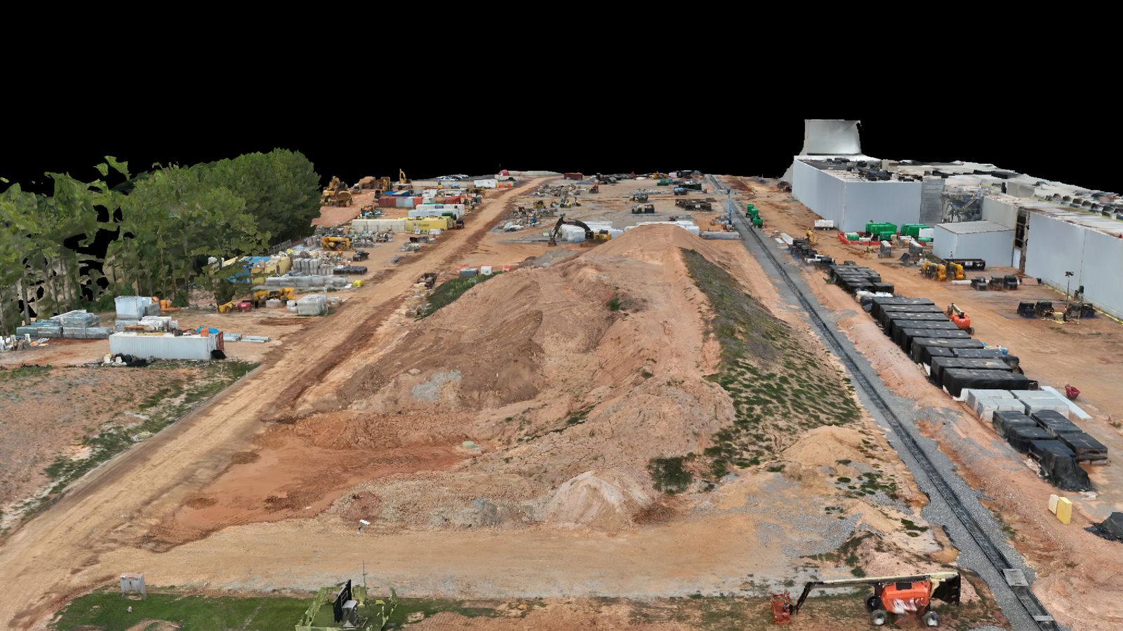 Aerial view of a large construction site with dirt roads, equipment, and parked vehicles along the edges