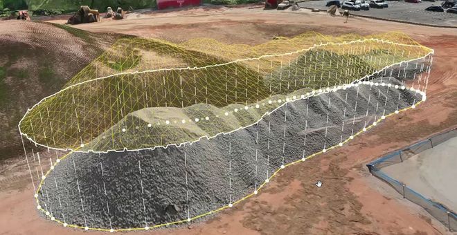 Aerial view of a terraced earthwork with white outline markings on a construction site.