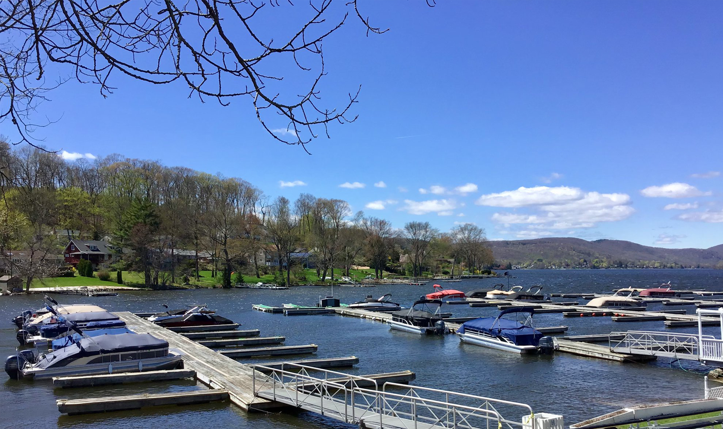A dock filled with boats on a lake on a sunny day.
