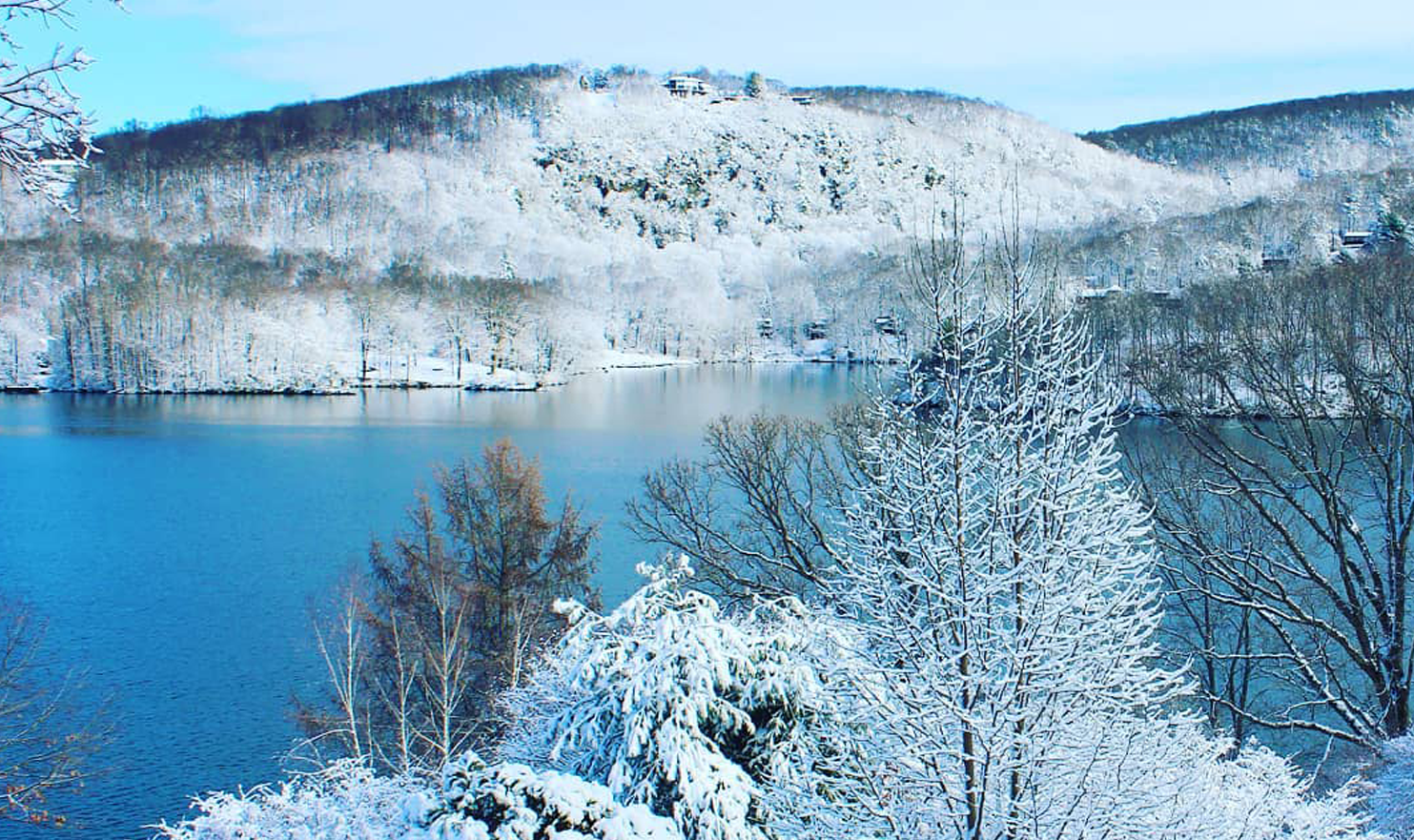 A lake surrounded by snow covered trees and mountains