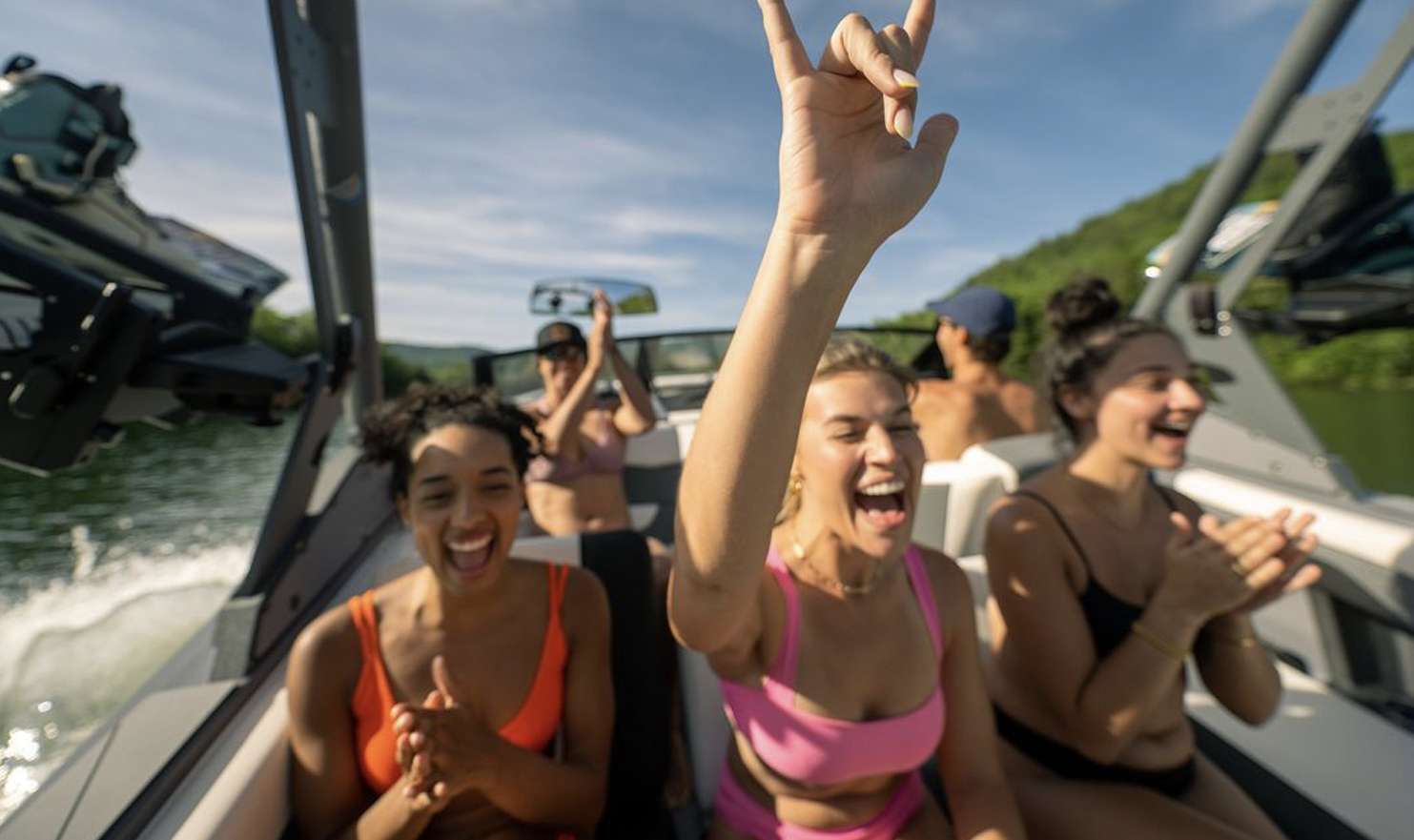 A group of women are sitting on a boat with their arms in the air.