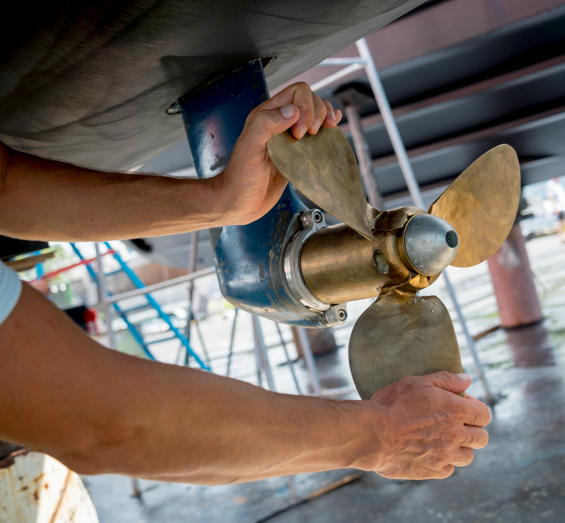 A man is working on the propeller of a boat.