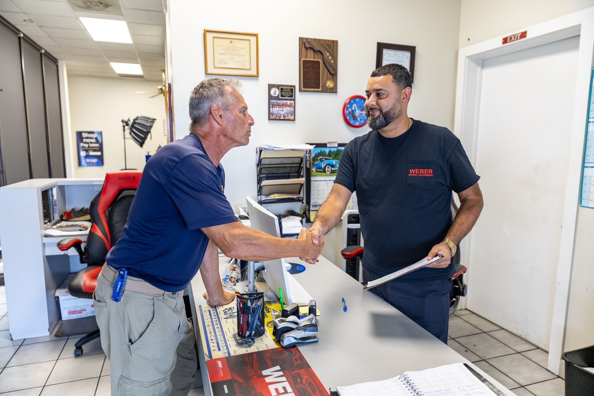 Two men shaking hands across a service counter in a bright office reception area