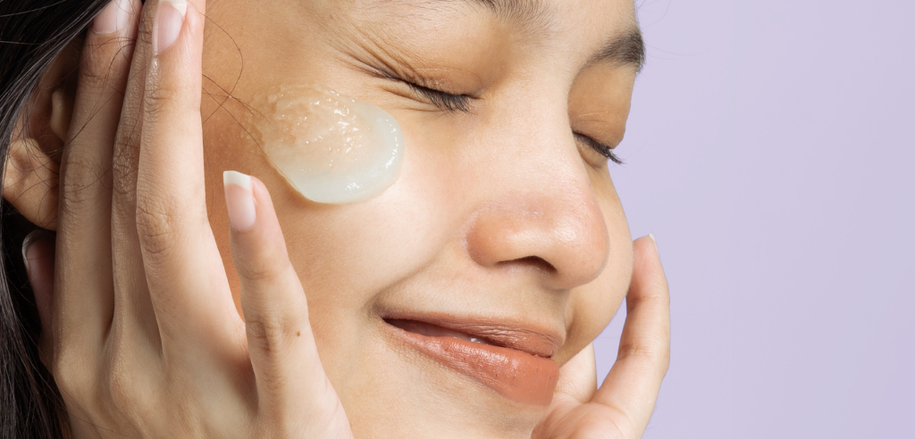 Woman smiles with skin care product on cheek