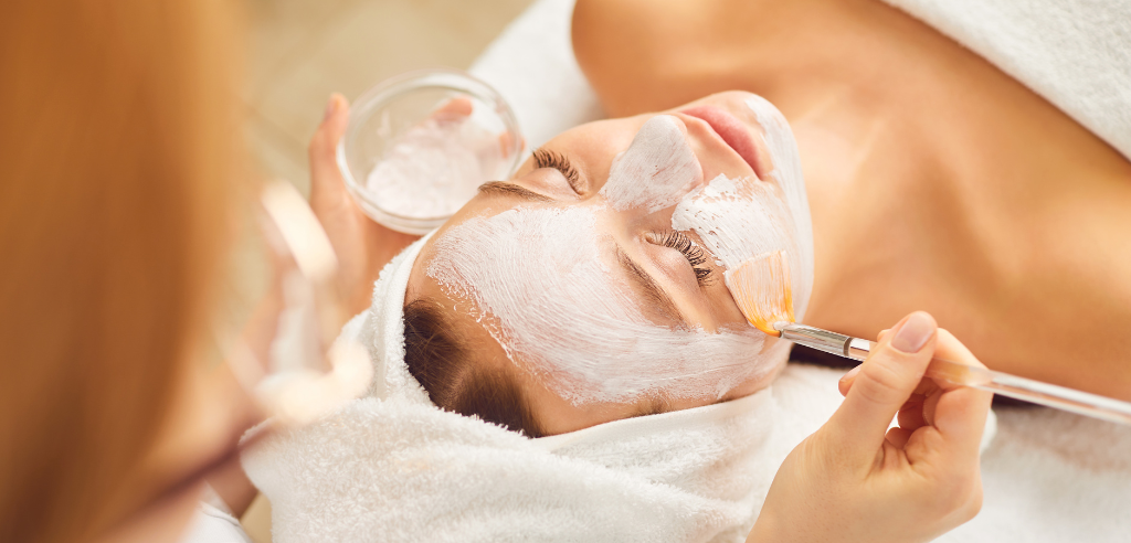 Esthetician applies face treatment to woman's face with small brush in spa setting