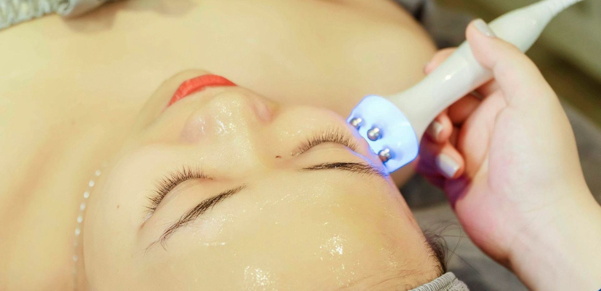 A woman is getting a massage with a LED Light on her face.
