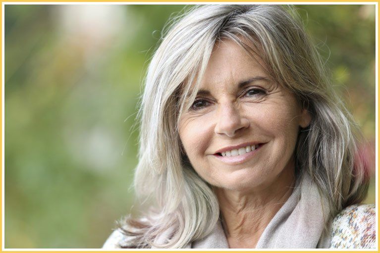 An older woman with gray hair is smiling for the camera.