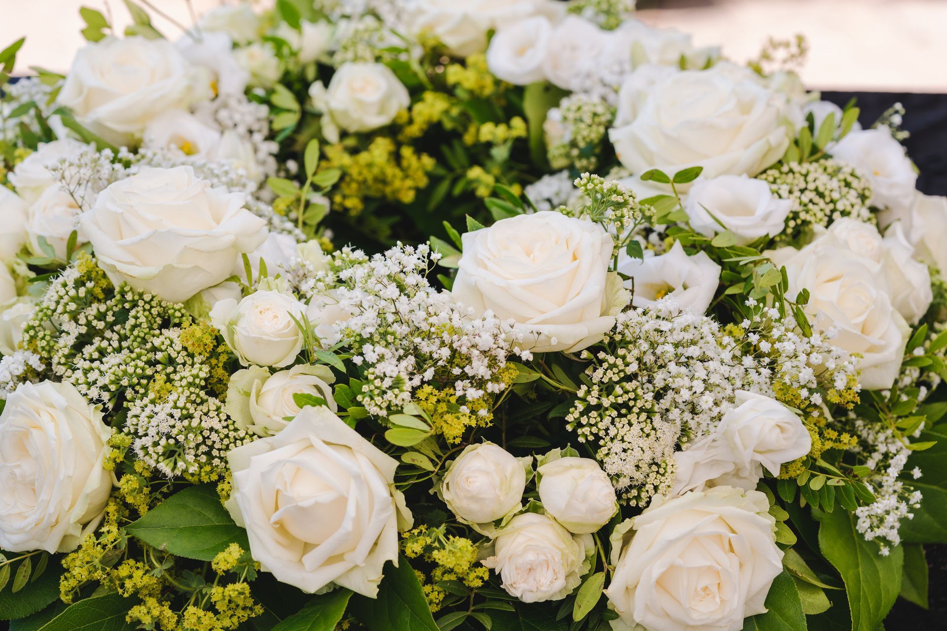 A close up of a wreath of white roses and baby 's breath.