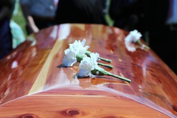 A wooden coffin with white flowers on it.