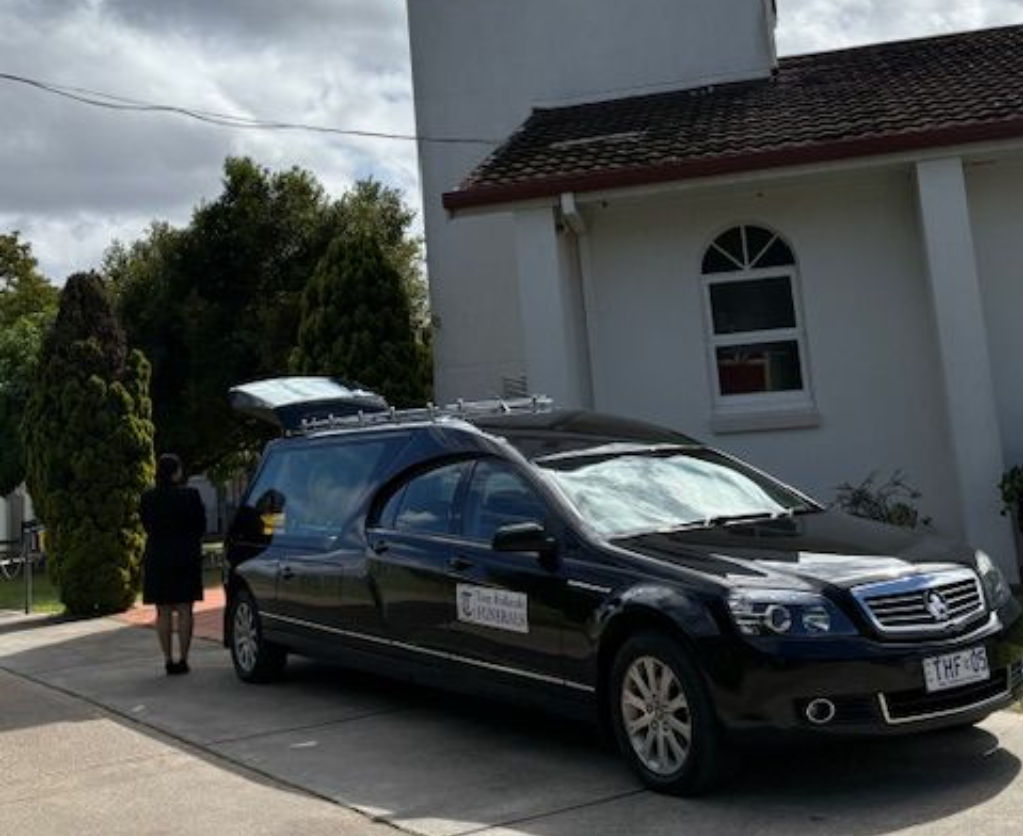 Image of a black Statesman Hearse outside a white church