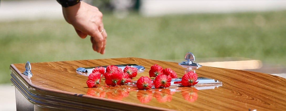 Image of remembrance red poppies being placed on a coffin