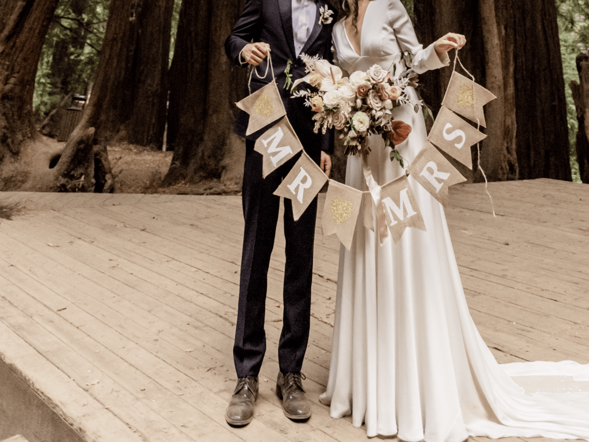 A bride and groom holding signs that say mr and mrs
