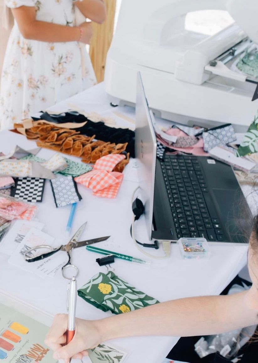 Desk with fabric swatches, scissors, laptop, and printer in a sewing or design workspace