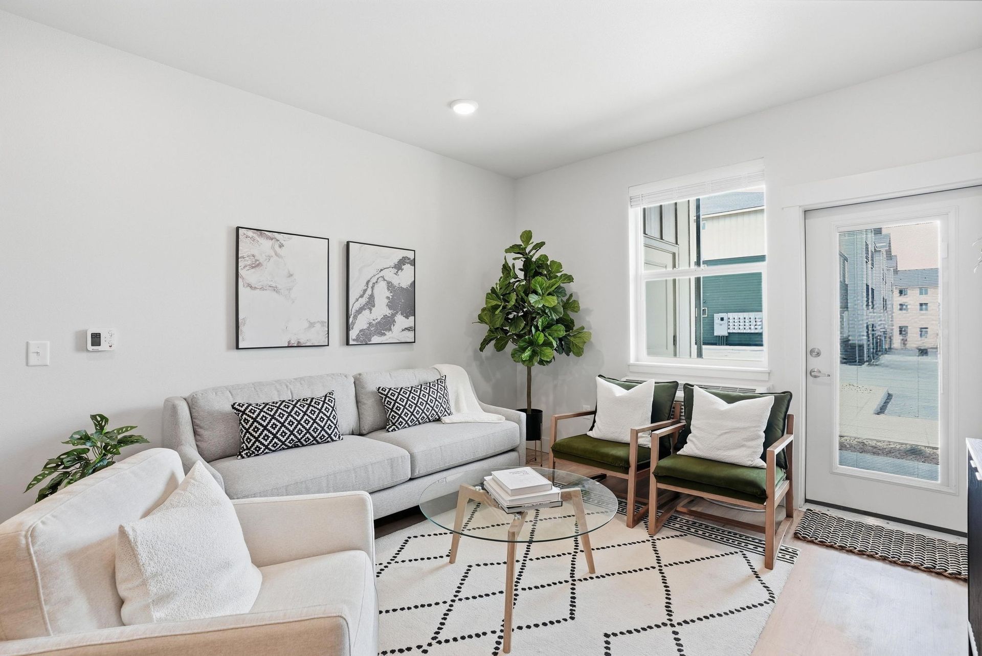 Bright modern living room with white sofa, chairs, coffee table, plants, and balcony doors
